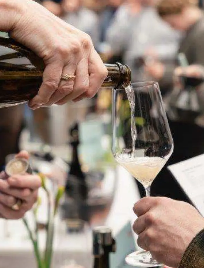 Someone pouring a glass of wine into another person's glass