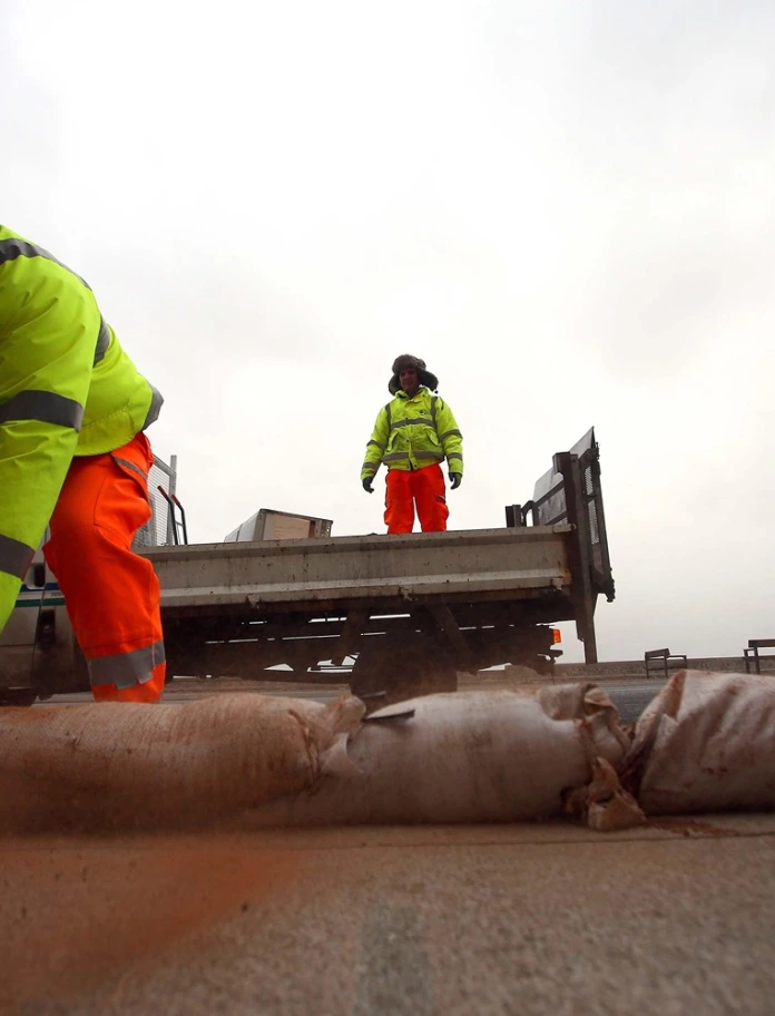 Workers putting out sand bags to protect against flooding